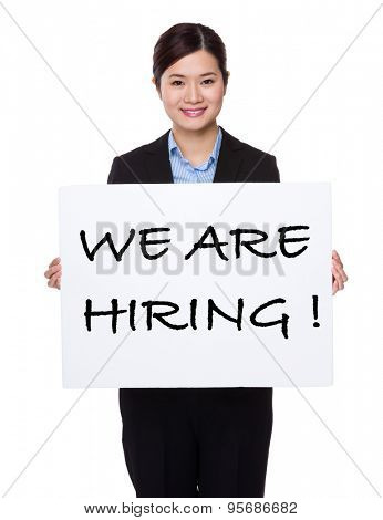 Businesswoman with white palcard for showing phrase of we are hiring  