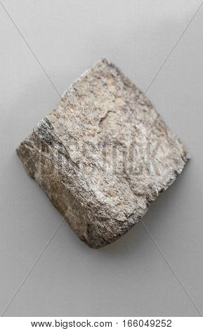 Piece of schist rock isolated over grey background. Metamorphic rock coming from Malaga mountains Spain
