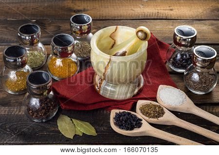 spices in spoons and Jar with mortar on a wodeen background