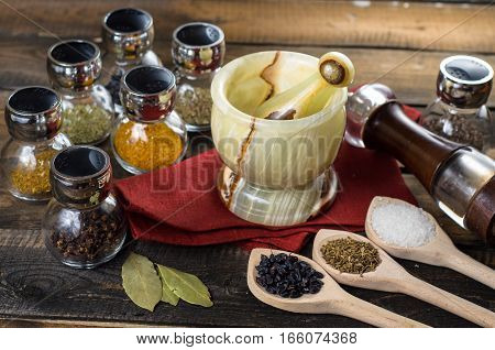 spices in spoons and Jar with mortar on a wodeen background