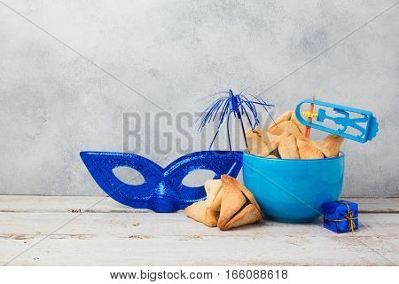Jewish holiday Purim concept with hamantaschen cookies or hamans ears and carnival mask over rustic background