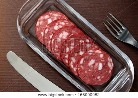 slices salami on a plate with cutlery
