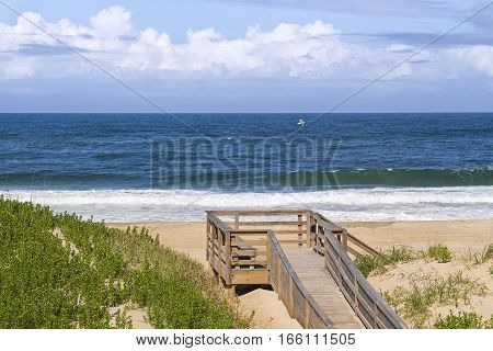 Waves break on a sandy North Carolina beach with a wooden boardwalk and deck on the dunes.