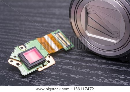 Sensor and lens housing of decomposed digital compact camera on black table