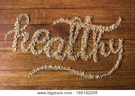 The word Healthy written oats on wooden background. Healthy food concept