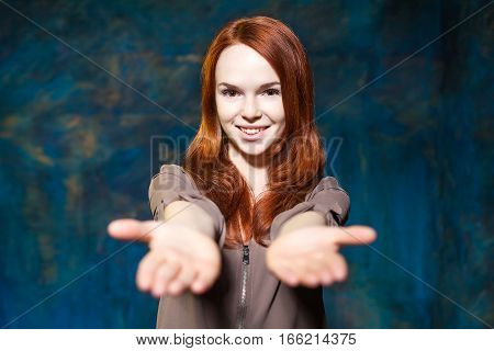 beautiful young girl with red hair stretching hands to the camera and smiling