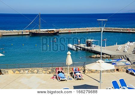 AGIOS NIKOLAOS, CRETE - SEPTEMBER 17, 2016 - Tourists relaxing on the Hotel Mirabello sun terrace with the harbour to the rear Agios Nikolaos Crete Greece Europe, September 17, 2016.