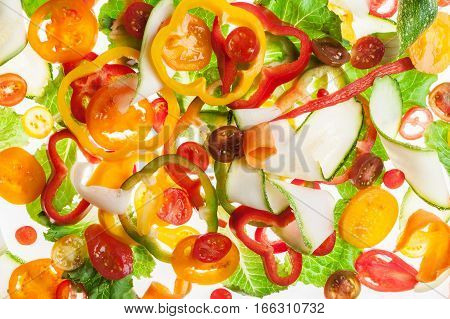 Mix of different red and yellow pepper and cucumber thin slices on white, pattern for textured background. Abstract art composition of fresh organic vegetables for salad mix