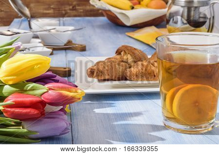 bright tulips, tea with lemon, pastries on a white plate