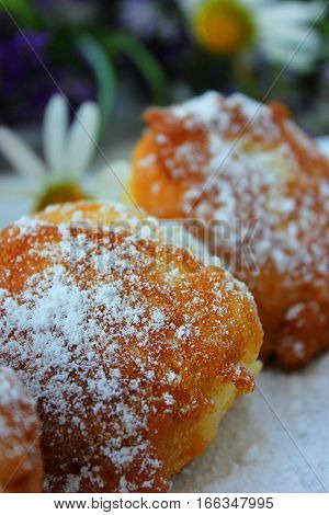 Sweet fried round doughnuts sprinkled with sugar powder on a plate. Pastry and desserts.