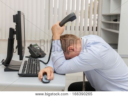 Young business man with problems and stress in the office sitting in front of the computer stock photo