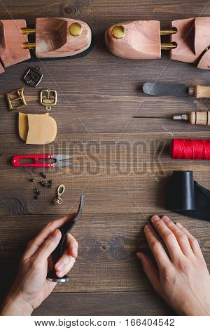 cobbler with tools work process dark background top view with hands