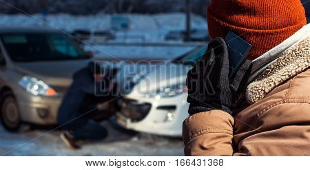 Sad male driver calling to car assistance service after auto crash. Two upset men on winter city street. Car collision.