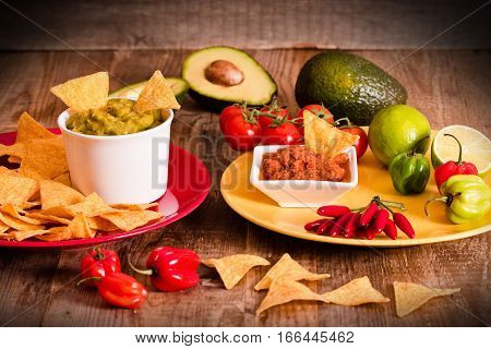 Guacamole and nacho chips on wooden table.
