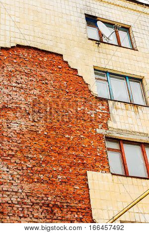 Old high-rise building with broken windows crumbling walls covered with cracks and scratches