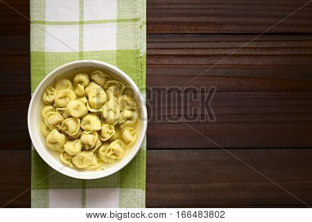 Traditional Italian Tortellini in Brodo (broth) soup photographed overhead on dark wood with natural light
