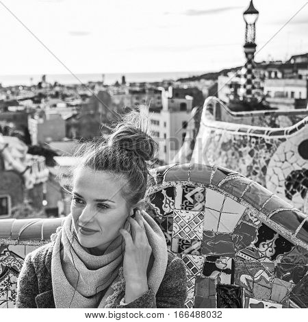 Woman In Barcelona Listening Audioguide While Sitting On Bench