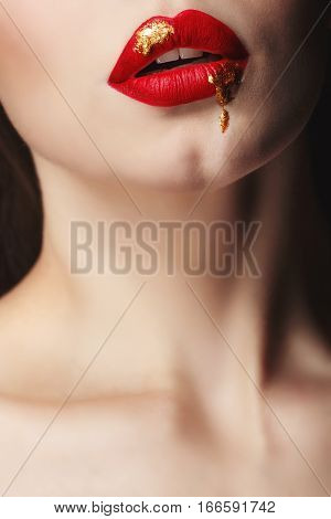 Sensual portrait of a girl with red lips and liquid paint on her face. Makeup simple and catchy. Close-up of mouth. Girl vamp.