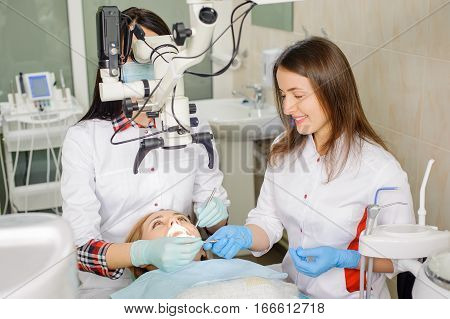 Female Dentist Treating Caries Using Microscope At The Dentist Office