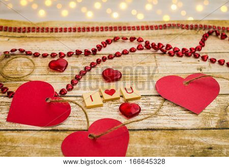 I heart U spelled out flat with wooden block letters with hearts and decorative elements on wooden board