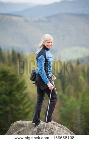 Female Climber On The Peak Of Rock With Climbing Equipment