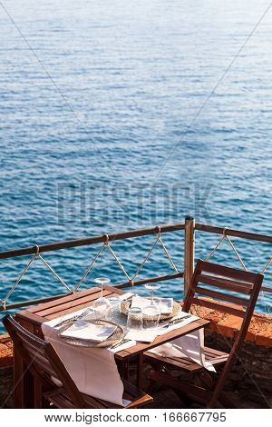Wooden table with white dishwater and chairs on ocean in a restaurant in Italy Europe