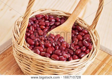 Raw adzuki red beans in woven basket on wooden background