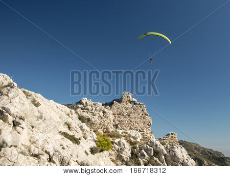 Green paraglider over the deep blue sky