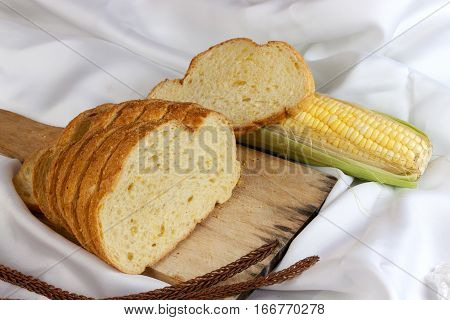bread made from corn on the white fabric. Slices of corn bread laying on a chopping Board and Sweet corn cobs