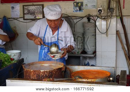 Hawker Vendor At Their Assam Laksa Noodle Stall In Air Itam, Penang
