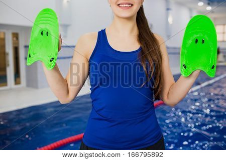 swimmer hands holding swimming blades. On the background blue pool