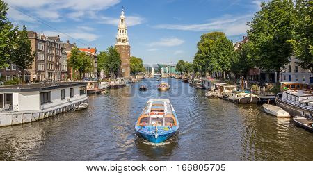 AMSTERDAM, NETHERLANDS - SEPTEMBER 18, 2016: Tourist cruiseboat and historical tower in Amsterdam, Holland