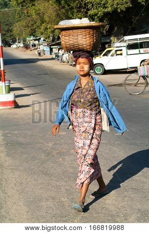Thazi Myanmar - 11 January 2010: Woman carrying products in a basket on her head walking on the street of Thazi on Myanmar