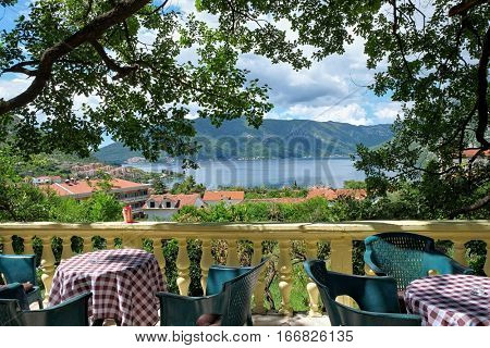 RISAN, MONTENEGRO - YULY 17, 2016: picturesque view, framed with oak fronds, on Kotor Bay from a terrace with balustrade
