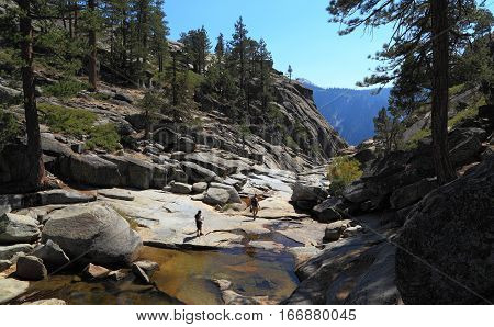 YOSEMITE NATIONAL PARK - SEP 21: Two hikers explore the dry, rocky creek bed of Yosemite Creek near the edge of Upper Yosemite Fall on Sep 21, 2015 at Yosemite National Park.