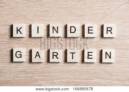 Alphabet letters on wooden pieces collected to word kinder garten
