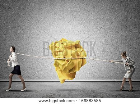 Two businesswomen playing tag of war game