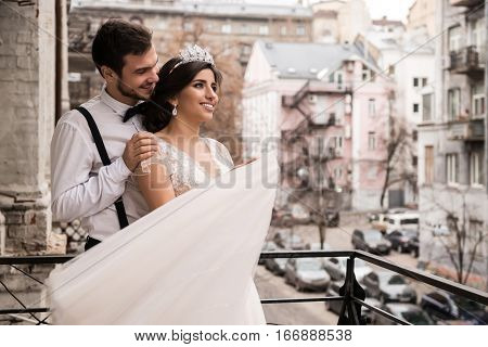 The bride and groom embrace on the balcony. Couple hugging on the balcony and enjoy life