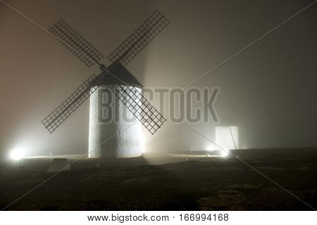 Windmills wrapped in a cold night with fog