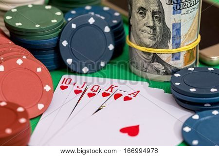 10 to Ace heart straight flush on poker and casino chips money on green table