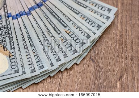 one hundred dollar bills on wooden table