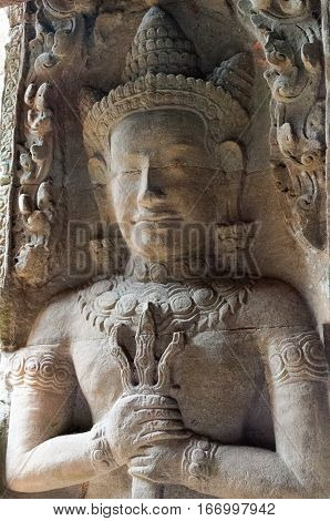 A carving of a dvarapala or guardian beside a doorway depcited with a mace in his hands