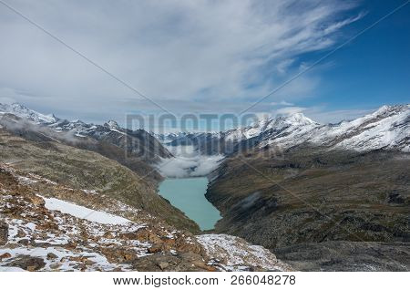 View To Stausee Lake Near Saas Fee In The Southern Swiss Alps From Monte Moro Pass, Italy