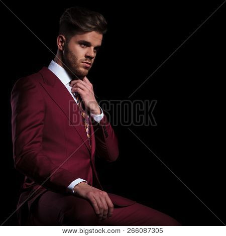 fashion businessman fixing his tie on a black background