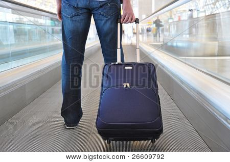 Cestovatel s kufrem na speedwalk