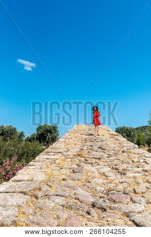 Girl In Red Dress Standing On Ancient Bridge