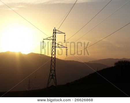 silueta de la torre de electricidad y cables en la puesta de sol en la cresta de las montañas