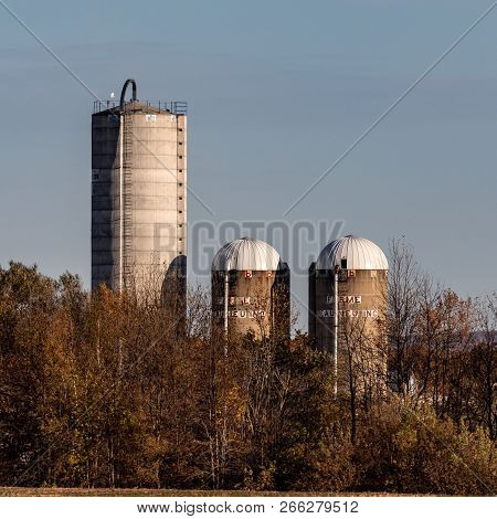 Near Howick, Quebec, October 14, 2018 -- Square Close Up Of Three Stilos Rising Behind Autumn Trees,