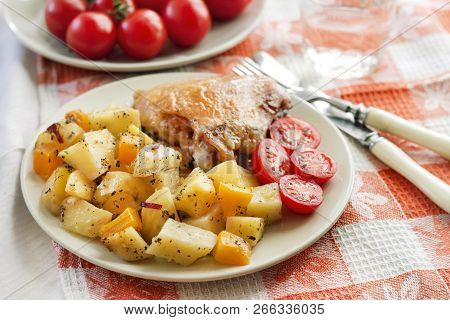 Baked Chicken Thigh With Baked Potatoes And Pumpkin Garnish On A Plate
