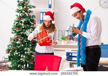 Colleagues exchaing christmas presents in office